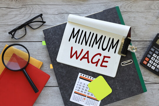 Minimum Wage text on a notebook on a folder. red notepad. magnifying glass