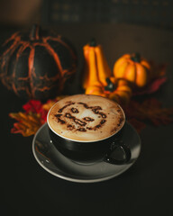 Halloween cappuccino coffee with a scary spooky pumpkin latte art and decorations