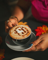 Girl holding a Halloween cappuccino coffee with a scary spooky pumpkin latte art and decorations