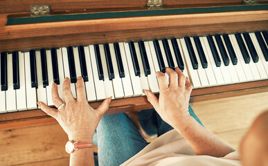 Hands, piano and senior woman playing for music in living room for musical entertainment practice. Instrument, hobby and elderly female person in retirement enjoying a song on keyboard at modern home
