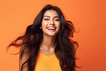 Young and beautiful woman loudly laughing on yellow background.