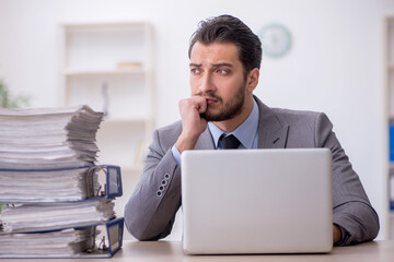 Young male employee and too much work in the office