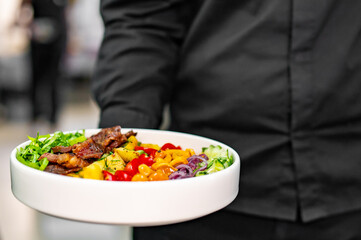 chef or waiter hold plate of Cobb salad