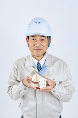 住宅模型を持つ作業服の中年男性　作業員　建設業者