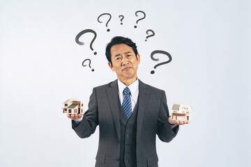 住宅模型を持って悩む中年ビジネスマン