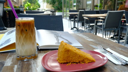 A slice of cake, a glass of cold coffee and book