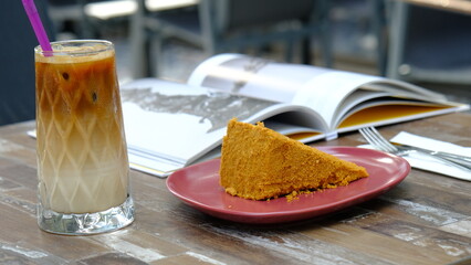 A slice of cake, a glass of cold coffee and book