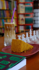 Naklejka na ściany i meble a slice of cake, a glass of cold coffee, book and chess board