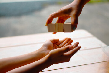 Square wooden blocks and hands, in the idea add words to the wooden blocks. such as the word 