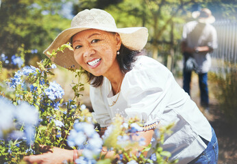 Portrait, mature and woman for gardening with hat, landscaping and backyard in spring. Asian person, grandmother and love with smile for blue flowers in bloom for peace, relax or wellness for care
