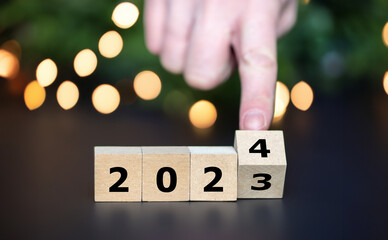 Hand turns cube and changes the year 2023 to year 2024.. - obrazy, fototapety, plakaty