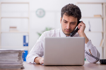 Young male employee and too much work in the office