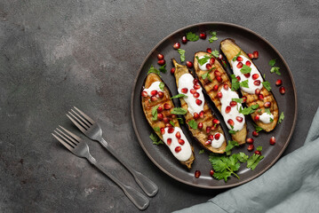 Grilled eggplants with garlic yogurt sauce and pomegranate. Top view, flat lay, copy space.