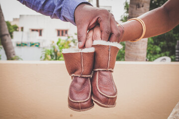 close up of couple hands holding a pair of baby boots