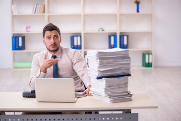 Naklejka premium Young male employee unhappy with excessive work in the office