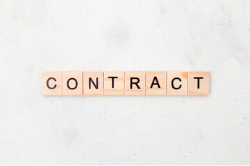 Fototapeta premium Top view of contract word on wooden cube letter block on white background. Business concept