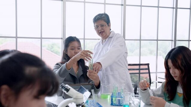 Cute Asian elementary school student is experimenting with mixing colors in science test tube with classmates. Learn to experiment in school laboratory. There will be teachers nearby ready give advice