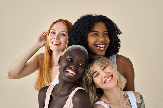 Happy positive cool diverse young women, four smiling multiethnic beauty faces models gen z girls friends group in underwear bras hugging laughing isolated on beige background, portrait.