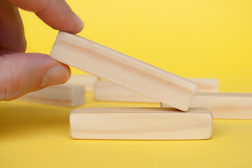 Hand placing wooden block on yellow cover with customizable space to insert text. Copy space