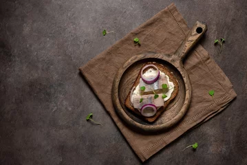 Foto op Aluminium Herring sandwich with rye bread ,red onion and microgreens, dark rustic background. Top view, flat lay. © Yulia