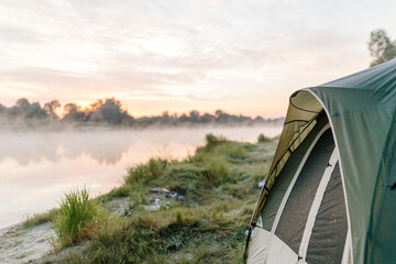View from the tent of the foggy river in the morning. Camping. Meeting the dawn on the lake.