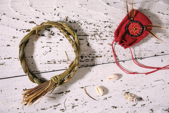 Sweetgrass braid (Hierochloe odorata), also called vanilla grass, and medicinal pouch on old white wood. High angle view, flat lay.