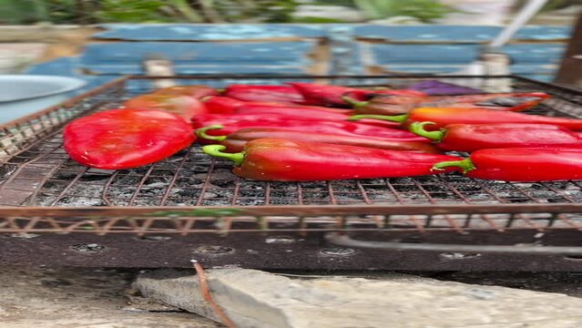 Red bell peppers being roasted on outdoor grill