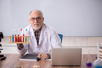 Old male teacher chemist sitting in the classroom