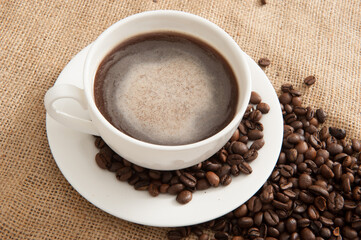 Cup of coffee on a saucer with coffee beans