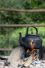 Blackened kettle over open flame brewing in a tea plantation
