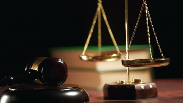 A judge is hitting gavel off a block in courtroom. Close up of scales of justice and legal lawyer books or codex. Sentence or win at auction. Law or legal system and jurisprudence or court concept.