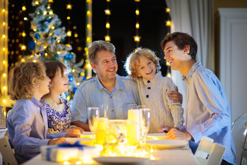Christmas dinner. Family with kids at Xmas tree.