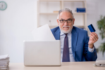 Old male employee holding credit card