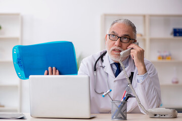 Fototapeta premium Old male doctor in telemedicine concept