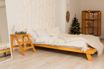 Christmas decorated bedroom interior with comfortable bed, Christmas fir tree and gift boxes on floor, copy space. Cozy home moment. Happy New Year. christmas garland lights at home © Yulia