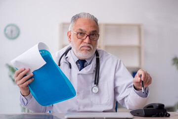 Old male doctor sitting in the clinic