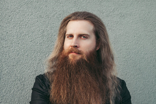 Man portrait Scandinavian european thirty years old long bearded with long loose red hair hairdresser barber serious with confident look and white teeth in black jacket and white shirt. concept