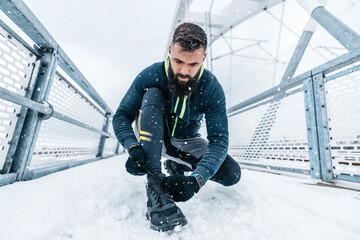 Handsome middle age man with a beard running and exercising outside on extremely cold and snowy...