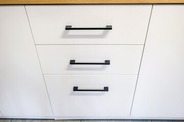 black metal handles on white nightstand cabinets and drawers on kitchen