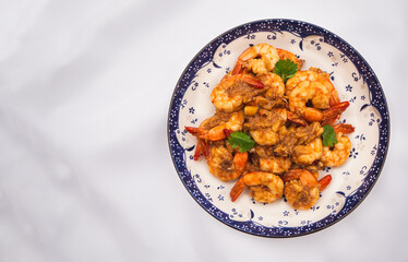 Top view of stir fried shrimps with garlic and white pepper in plate on white fabric background. Thai Food