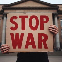 Manos levantado un cartel de cartón en el que se lee Stop War, para pedir el fin de la guerra
