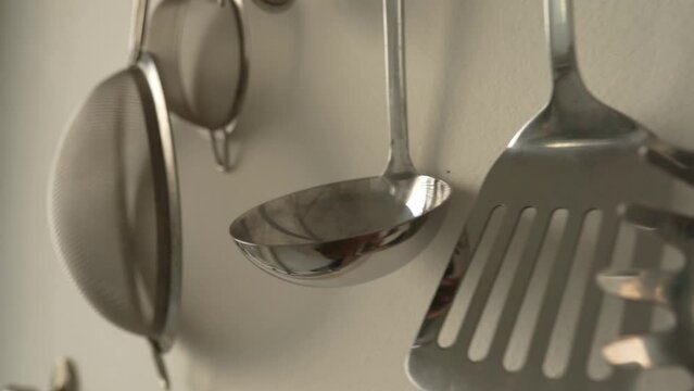 Slow motion view of kitchen utensils hanging on wall