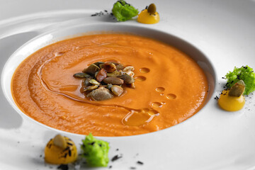 Pumpkin cream soup in a white plate. Close up