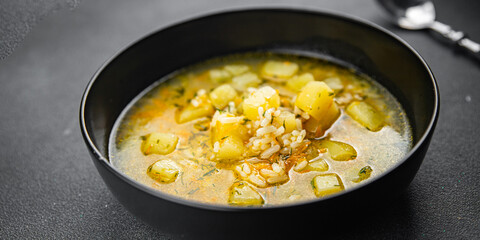 rice soup vegetable broth, potato, carrot, onion healthy eating cooking appetizer meal food snack on the table copy space food background rustic top view keto or paleo diet vegetarian vegan