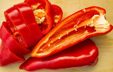 Fresh red pepper, cut in half, lies on a wooden board. Concept of healthy eating, cooking.