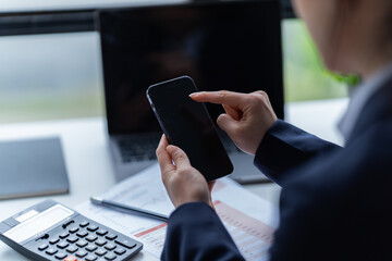 Asian businessman using laptop computer and smartphone contact business search information on desk in the office. checks mail, 