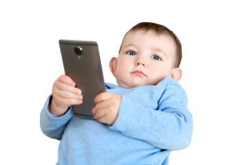 Surprised toddler baby boy is sitting with a phone on the sofa in the living room, isolated on a white background. Child with a smartphone in his hands on the bed