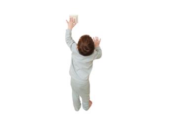 Little baby turns on the light by pressing the switch, isolated on white background. Small child turns off the electric light at the white door, isolated on white background. Kid aged two years