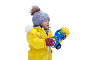 Happy toddler baby is playing with a toy in the snow in a yellow snowsuit, isolated on white background. Child boy in warm clothes walks in winter park. Kid aged one year six months