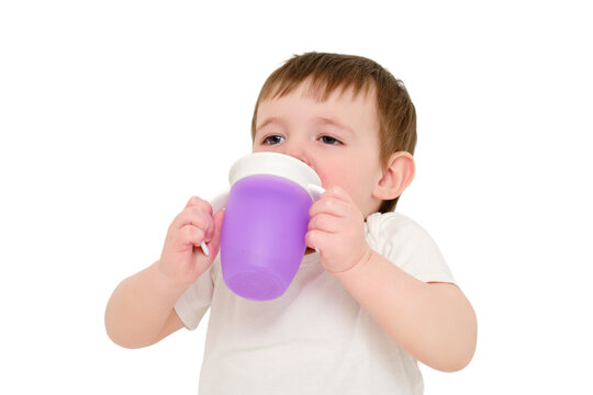 Happy baby drinks water from cup on studio, isolated on white background. Resting child with cup juice in hands, isolated on white background. Kid about two years old (one year nine months)